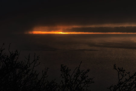 Orange light over dark misty foggy lake Liptovska Mara, Slovakia.