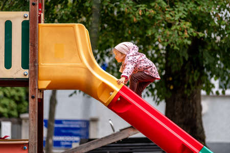 Small crazy girl playing on slide in playgroundの写真素材