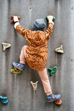 Small boy climbing a rock wall and playing on the playgroundの写真素材