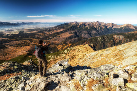 Hiker at top of the peak making picture of beautiful mountain landscape in Slovakia.の写真素材