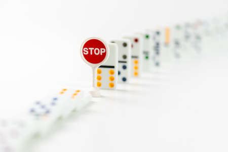 Falling dominos pieces stopped by text STOP. Chain reaction and domino effect conceptの写真素材