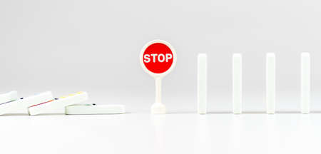 Falling dominos pieces stopped by sign STOP. Dominoes effect concept. Chain reactionの写真素材