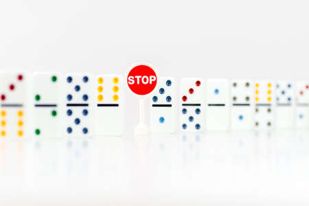 Red sign with text Stop and inside domino pieces on a white background. Risk and strategy dominoes concept.の写真素材