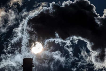 factory skomestack and coming out dark smokes in the sky and sun at background.の写真素材