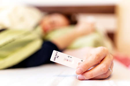 Patient with coronavirus Covid-19 lying in bed with positive test result of antigen test.の写真素材