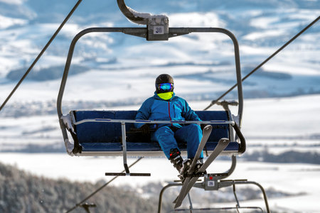 VALCA, SLOVAKIA - JANUARY 22, 2022: Skier sitting on ski-lift chair or chairlift at resort Snowland...