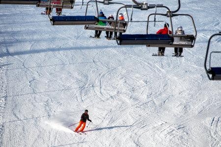 VALCA, SLOVAKIA - JANUARY 22, 2022: People sitting on chairlift and skiers skiing downhill on slope at mountain resort SNowlandのeditorial素材
