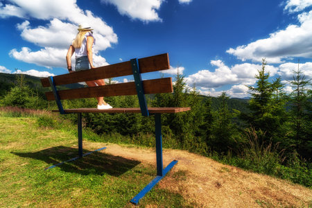 OSCADNICA, SLOVAKIA - JULY 29, 2021: Lonely girl sitting on large xxl bench and looking on beautiful...