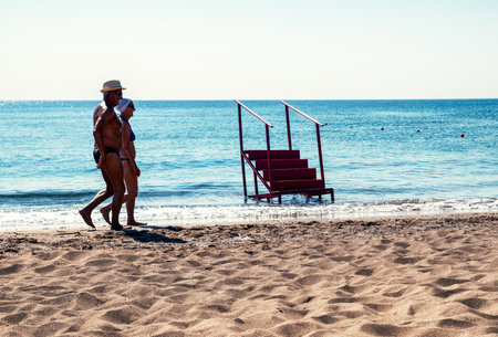 FALIRAKI, GREECE - JUN 30, 2022: Senior couple walking on sandy beachのeditorial素材