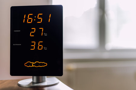 Hot summer day. High temperatures showing on display of home meteo station. Sun shine through window.の写真素材