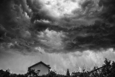 Dark stormy clouds over house on the hillの写真素材