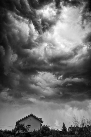 Dark stormy clouds over house on the hillの写真素材
