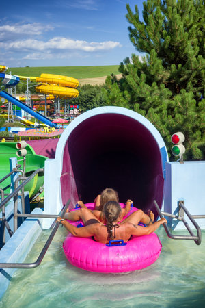 Liptovsky Mikulas, Slovakia - August 4, 2022: People ready to slide on pink inflatable in water slide in aquapark Tatralandia in Slovakiaのeditorial素材