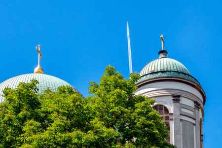 Golden cross on roof of  Esztergom basilica and airplane on blue sky.の写真素材