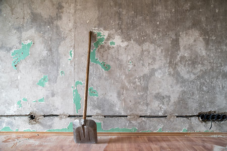 shovel leaning against an old wall. apartment under reconstruction. making new electricity in house.の写真素材