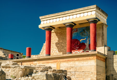 Famous red columns of the ancient Minoan palace in Knossos, Crete, Greece, with a colorful bull fresco, important archaeological site and symbol of Minoan civilization.の写真素材