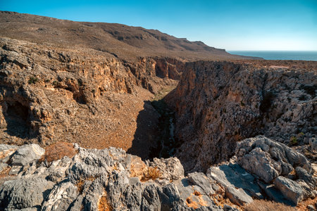 Panoramic view of Zakros Gorge, also known as the Valley of the Dead, on Crete, Greece, showing steep rocky cliffs and dry summer landscape.の写真素材