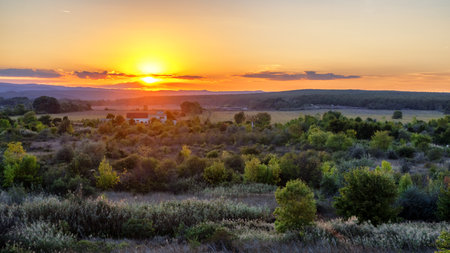 Beautiful countryside sunset near Obzor, Bulgaria with fields, trees and gentle hills in golden evening light. Peaceful rural summer landscape and nature scenery.の写真素材