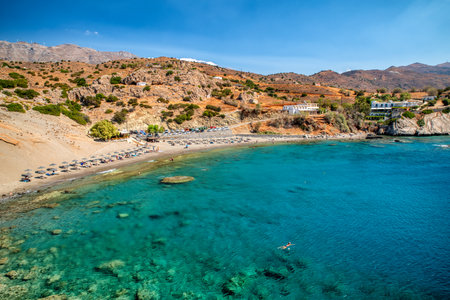 Agios Pavlos Beach, Crete, Greece: Calm bay with turquoise water and sandy shore surrounded by rocky hills and few visitors enjoying the peaceful Mediterranean coast.の写真素材