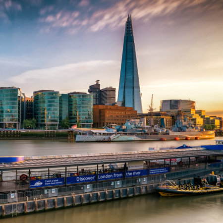 Panoramic view of the London skyline at sunset with The Shard skyscraper and modern riverside buildings reflecting warm evening light on the River Thames.の写真素材