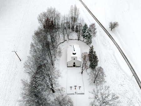 Drone view of the Calvary chapel in Ruzomberok with snowy trees and white fields around it. A quiet winter landscape shows the Church of the Exaltation of the Holy Cross in the Liptov region.の写真素材
