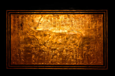 Detailed close up of a golden shrine panel from Tutankhamunâs burial chamber showing the sacred bull and hieroglyphs, highlighting ancient Egyptian art, symbolism and craftsmanship.の写真素材