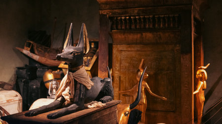 Anubis statue surrounded by Egyptian artifacts in a detailed museum display at the Tutankhamun exhibition.の写真素材