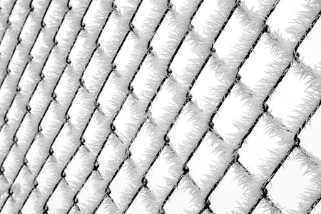 Detailed view of chain link fence coated in thick frost and ice crystals. Strong graphic winter...