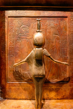 Ancient Egyptian ritual statue featuring carved hieroglyphs and symbolic reliefs displayed in a...