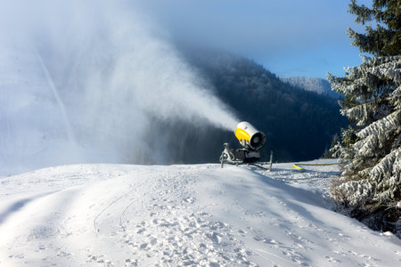 Malino Brdo, Slovakia - December 25, 2025: Snowmaking machine produces artificial snow on ski slope while people with child watch winter preparation at ski resort.のeditorial素材