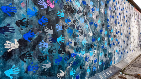 Berlin, Germany - April 8, 2017: Colorful mural with handprints on the Berlin Wall at East Side...