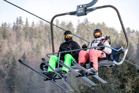 Ruzomberok, Slovakia - December 30, 2025: Skiers in colorful winter clothing riding a chairlift at mountain ski resort, highlighting winter sports, active tourism and dynamic atmosphere of ski season.のeditorial素材