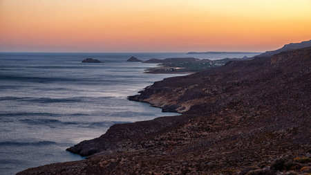 Rocky Mediterranean coastline and calm sea at sunset near Kato Zakros village on southern coast of...