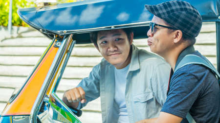 Asian travel photographer negotiates price with tuk tuk driver before traveling around Bangkok Landmark Thailand.の写真素材
