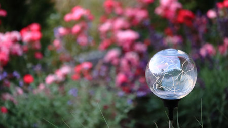 Glowing globe in the garden with blurred flowers in the background.