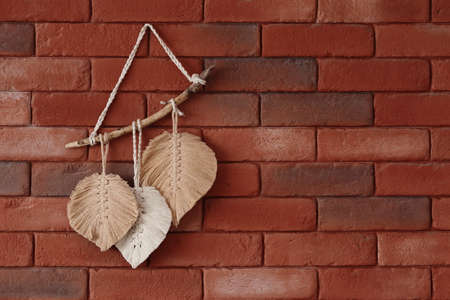 Boho style. A wall ornament in the shape of leaves hung on a brick wall.の写真素材
