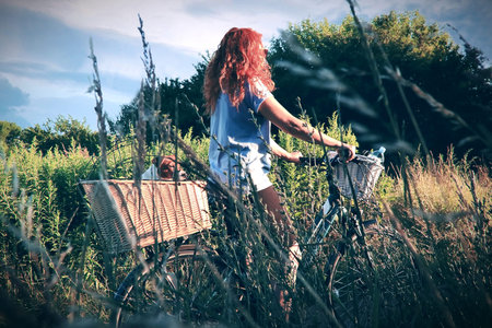 Retro, vintage photo. Bicycle trip with a dog in a basket on dirt roads.