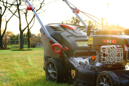 petrol lawnmower standing in the garden illuminated by the rays of the sunの写真素材