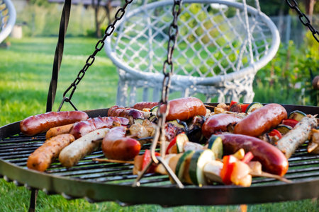 barbecue with delicious grilled sausages and vegetables on grill outdoorsの写真素材