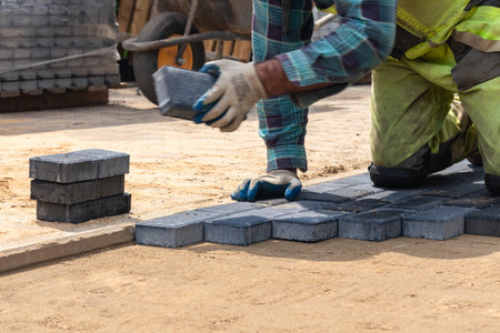 A worker laying paving stones at a sidewalk construction site, close upの写真素材