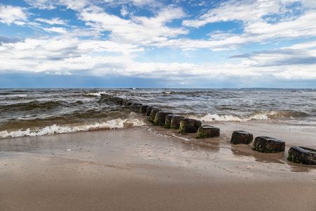Baltic sea shore with breakwaters and blue sky with clouds.の写真素材