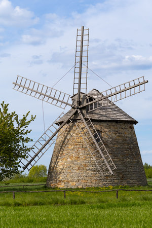 Old Dutch windmill. Built in 1880-1885. Standing on a green meadow with blue sky and clouds