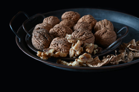 Whole and open raw walnuts on black background