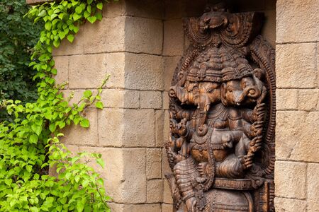 Brown wooden Ganesha at the temple surrounded by greenery.の写真素材