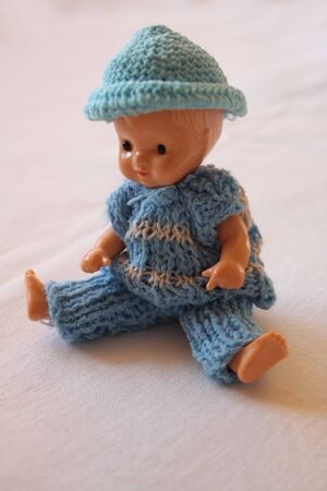 Old baby boy doll in a blue dress and hat.の写真素材