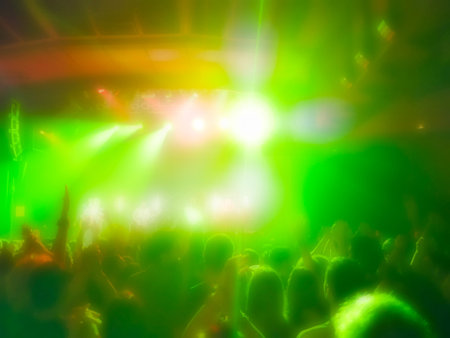 Concert crowd cheering in bright colorful lights with blurred effect.