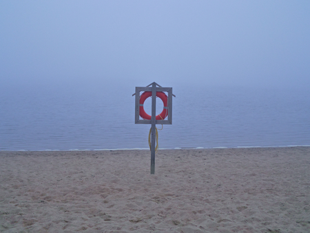 Life buoy on peaceful and misty beach by calm sea.の写真素材