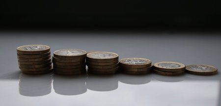 Euros stacked in piles with a white background and shadows of the piles are visible