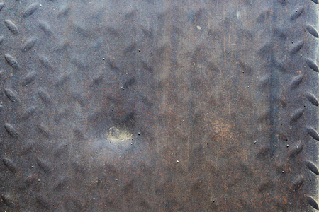 Close up of a worn out metal anti slip plate with a dent due to the many cars that drove over itの写真素材