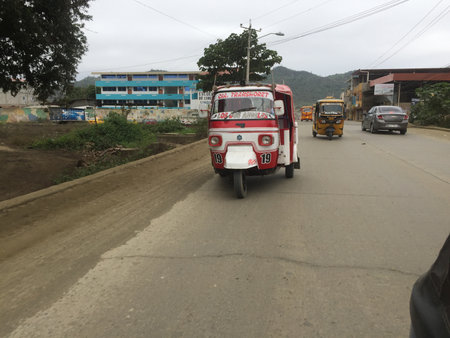 Puerto Lopez, Ecuador, 9-7-2019: a red tucktuck driving down the roadのeditorial素材